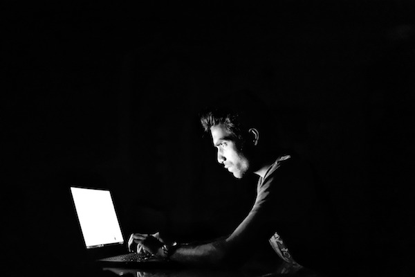 暗闇でパソコンをする男性